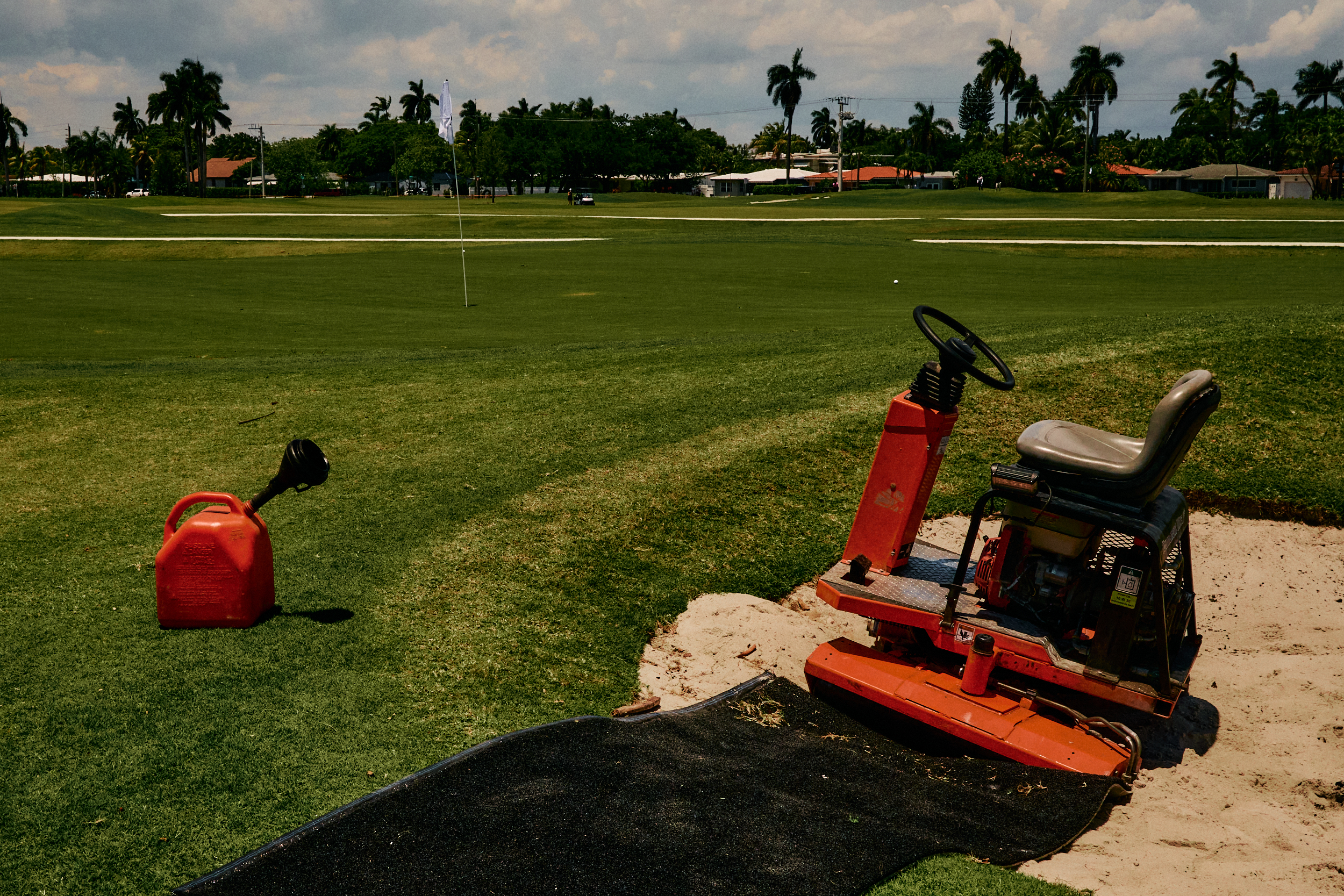 Golf course maintenance worker taking a lunch break beside a green roller.